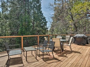 Relax on the deck surrounded by lush trees, with comfortable seating for dining or socializing.