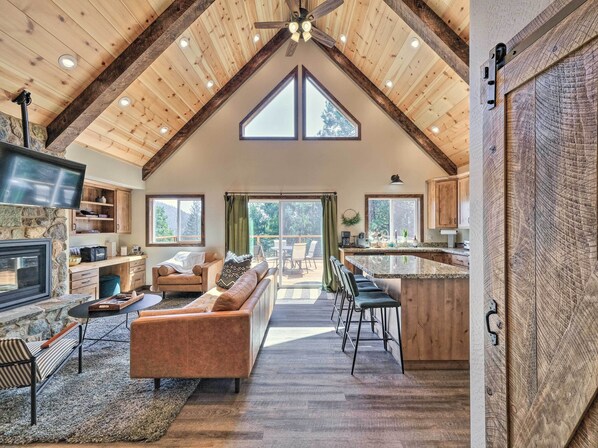 Enjoy an open and airy atmosphere with a spacious interior, featuring a cozy seating area, kitchen, and dining space with large windows offering views of the surrounding landscape.