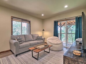 Relax in a serene space with a comfortable sofa, coffee table, and bean bag chair, offering a cozy seating arrangement and a view of lush greenery.