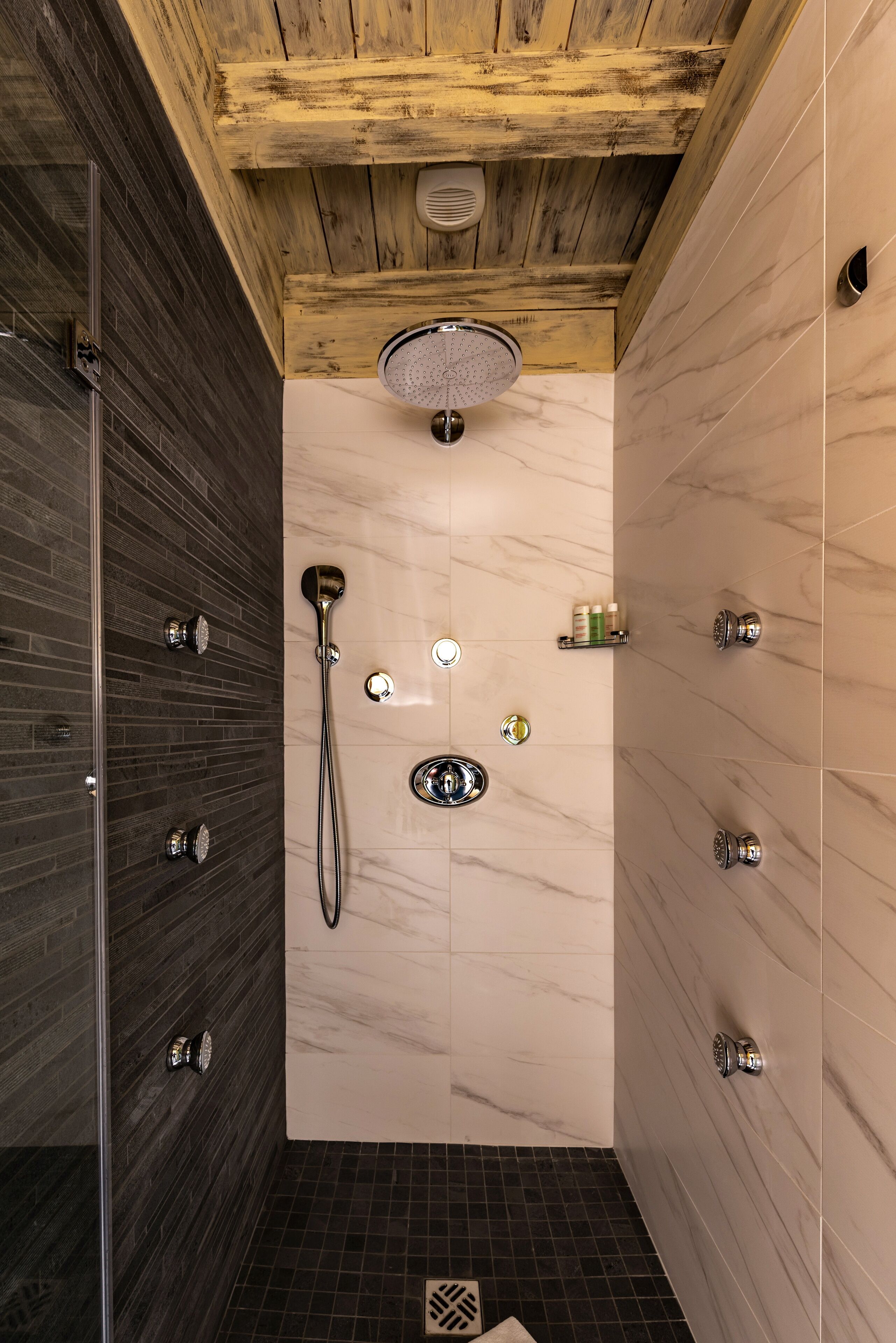 Un área de ducha moderna con múltiples cabezales y una cabina de ducha con mampara de vidrio.