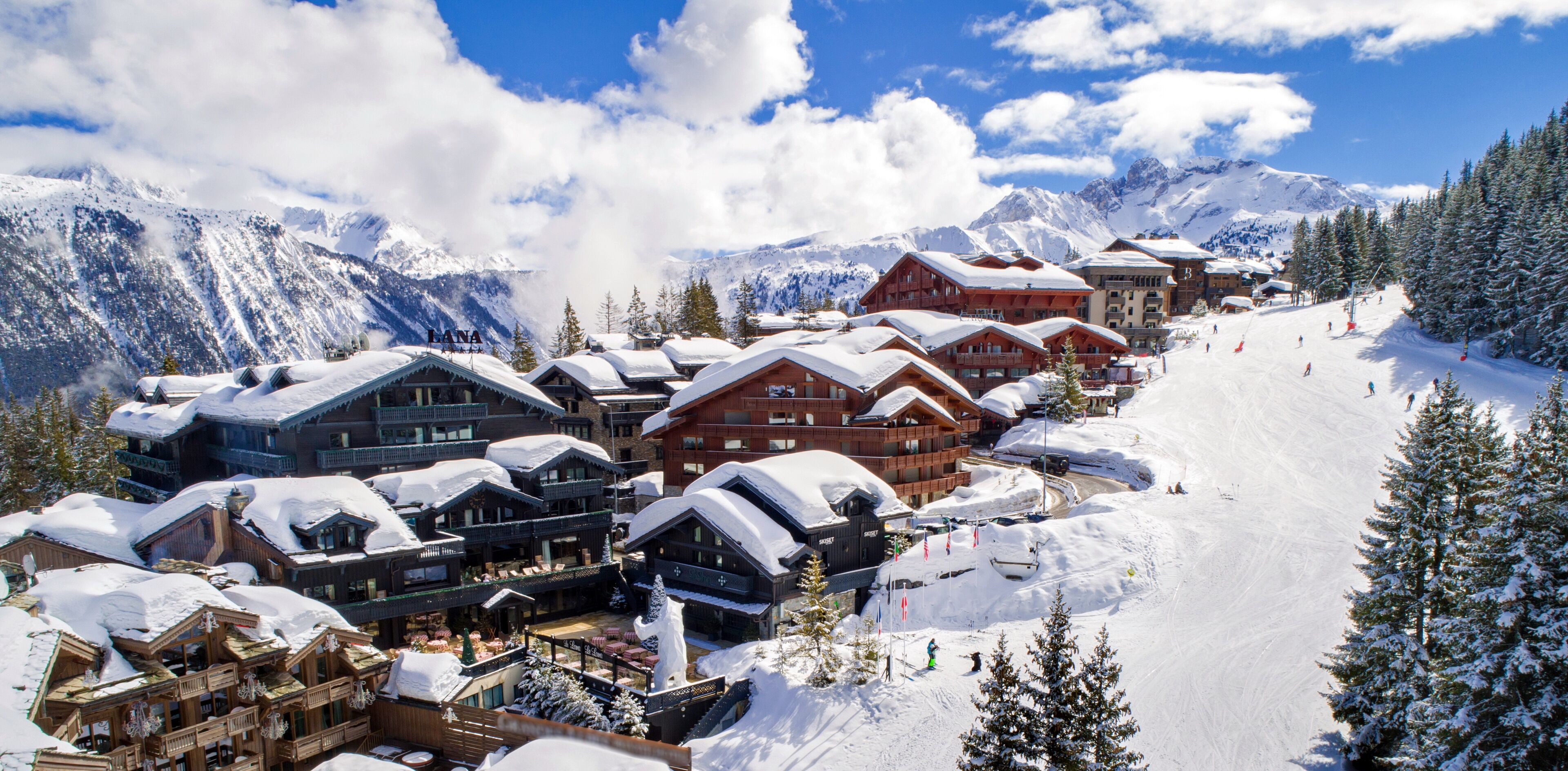 A snow-covered mountain resort with wooden buildings, ski slopes, and snow-covered trees.