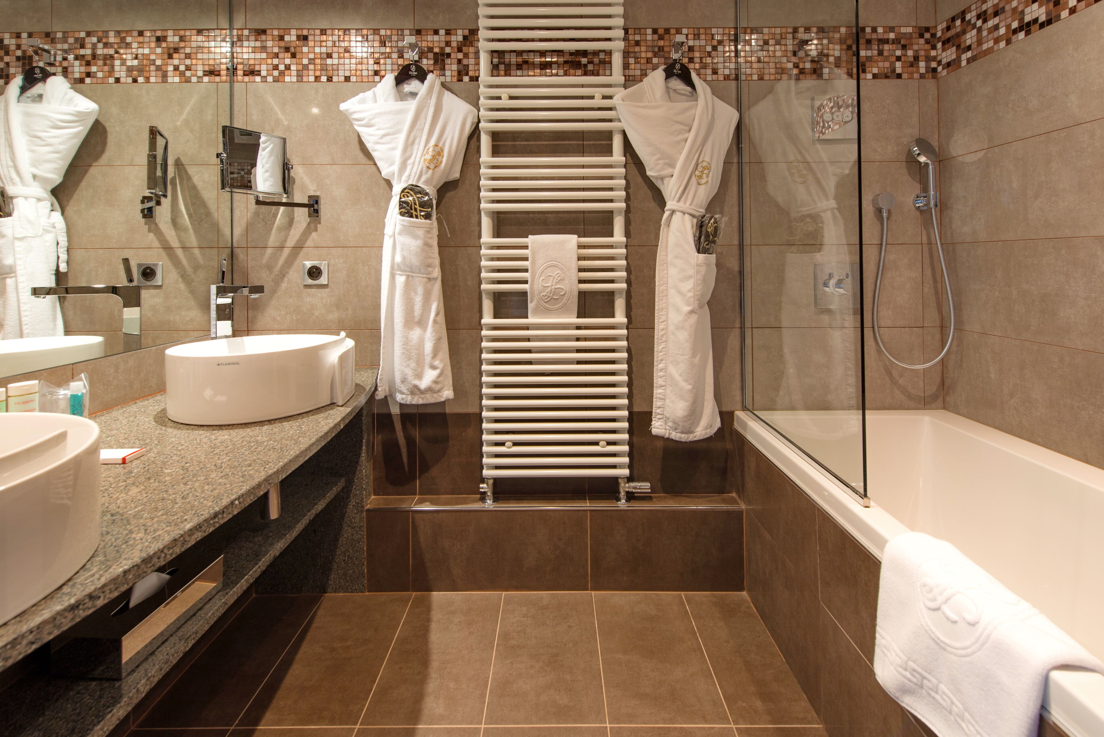 Un baño moderno con cabina de ducha de vidrio, toallero empotrado y tocador con lavamanos y espejo.