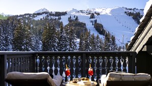 Un balcon offrant une vue sur un paysage montagneux enneigé, avec une piste de ski et des arbres.