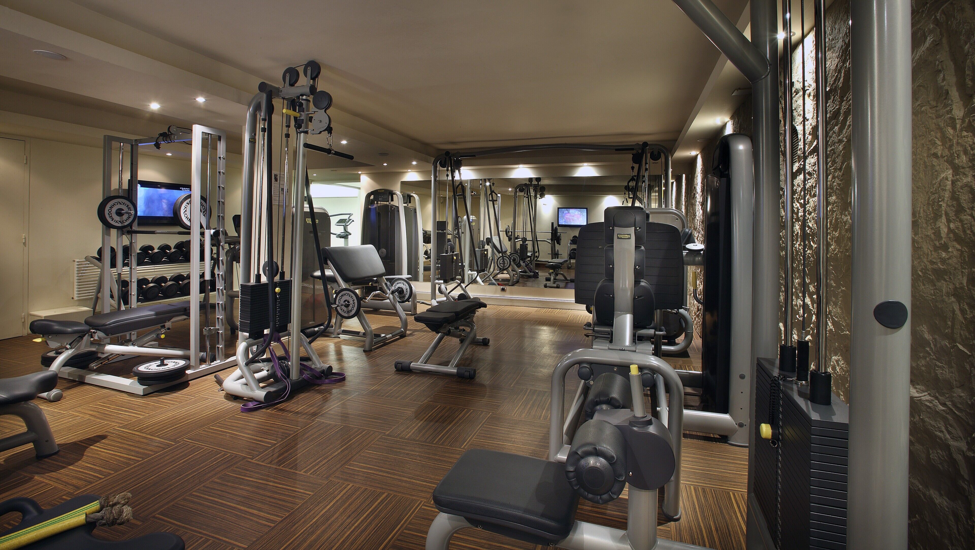 A gym with various exercise equipment, including treadmills, weight machines, and free weights.