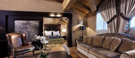 Una habitación con un sillón de cuero, un sofá, una mesita de centro con un jarrón de flores y una cama con cabecero.