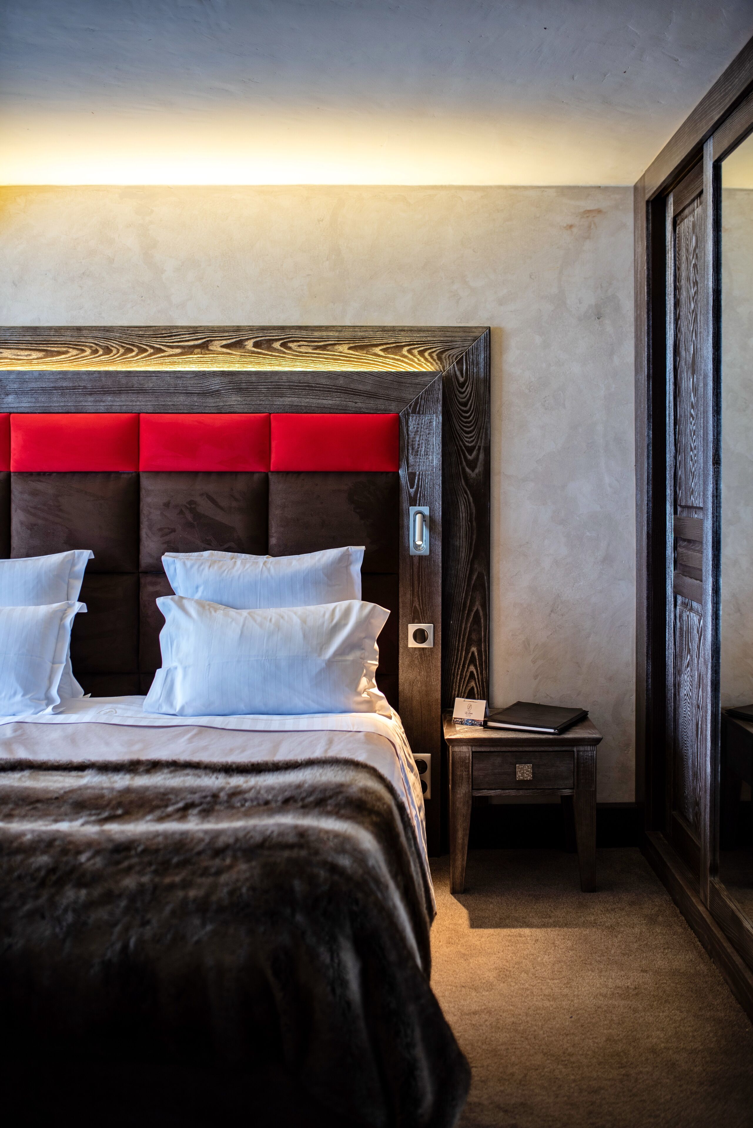 A bedroom with a large bed, a wooden headboard, a bedside table, and a nightstand.