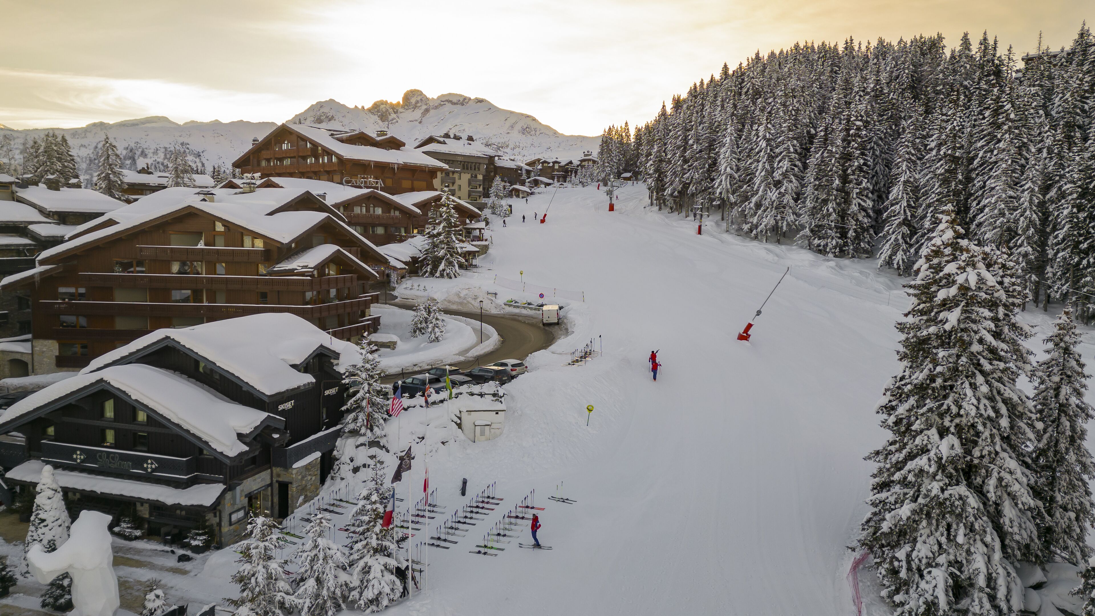 A ski resort with multiple wooden lodges, a ski slope, and snow-covered trees.