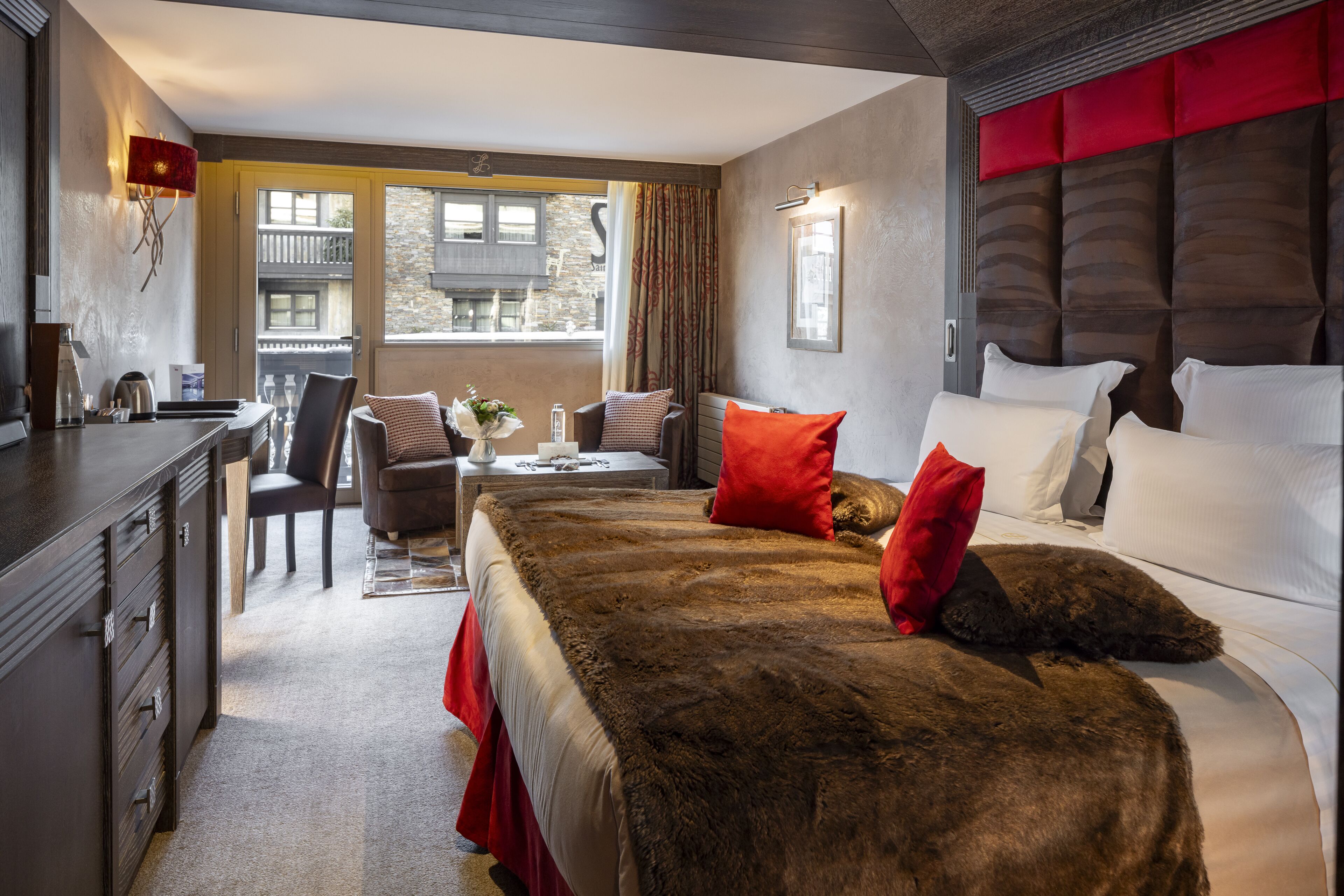A modern hotel room with a large bed, a desk, and a view of the city.