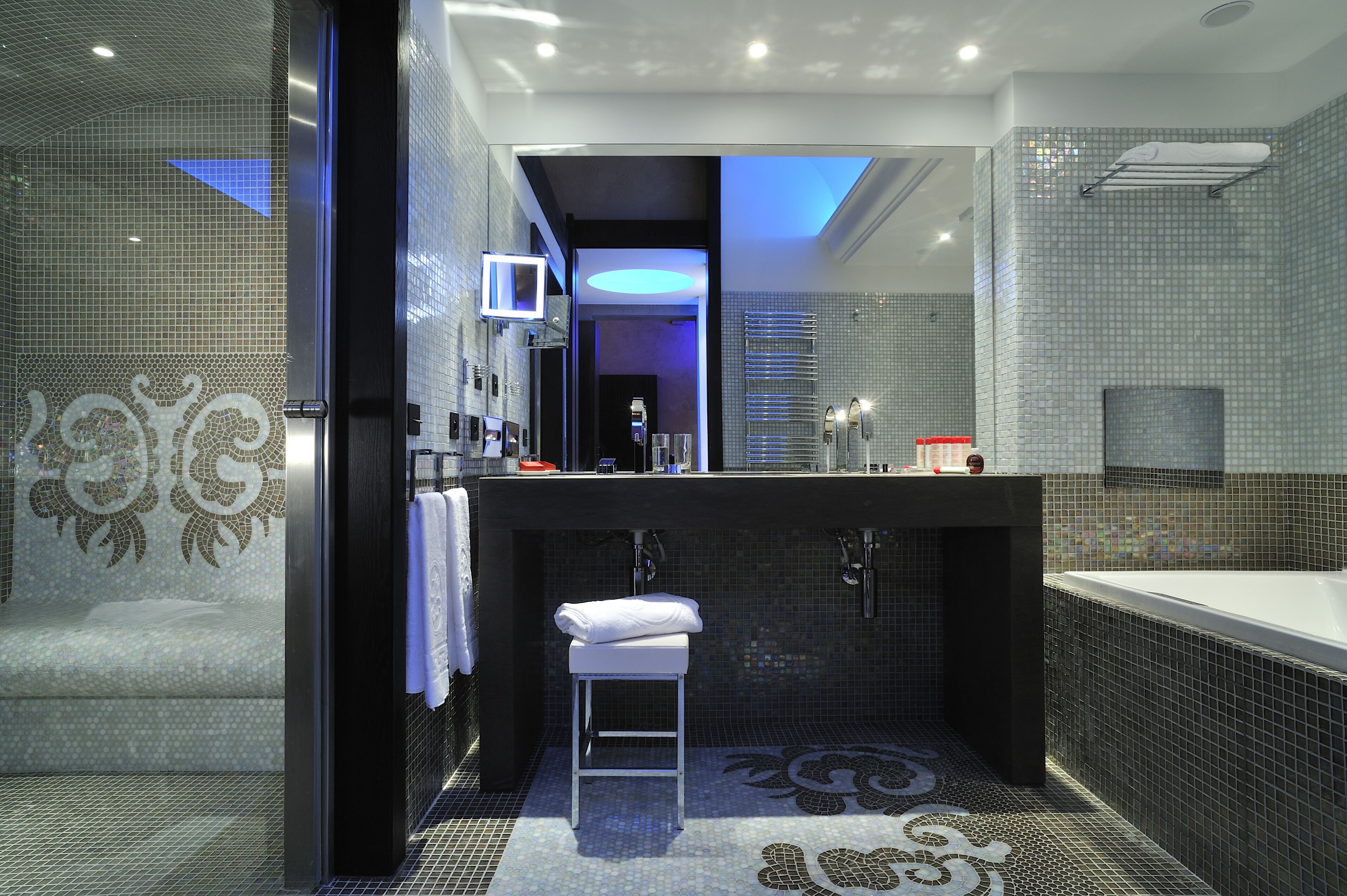 A modern bathroom with a large mirror, a bathtub, and a shower area.