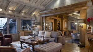 Un salon spacieux avec un plafond en bois, un grand ensemble de canapés, une table basse et une cheminée.