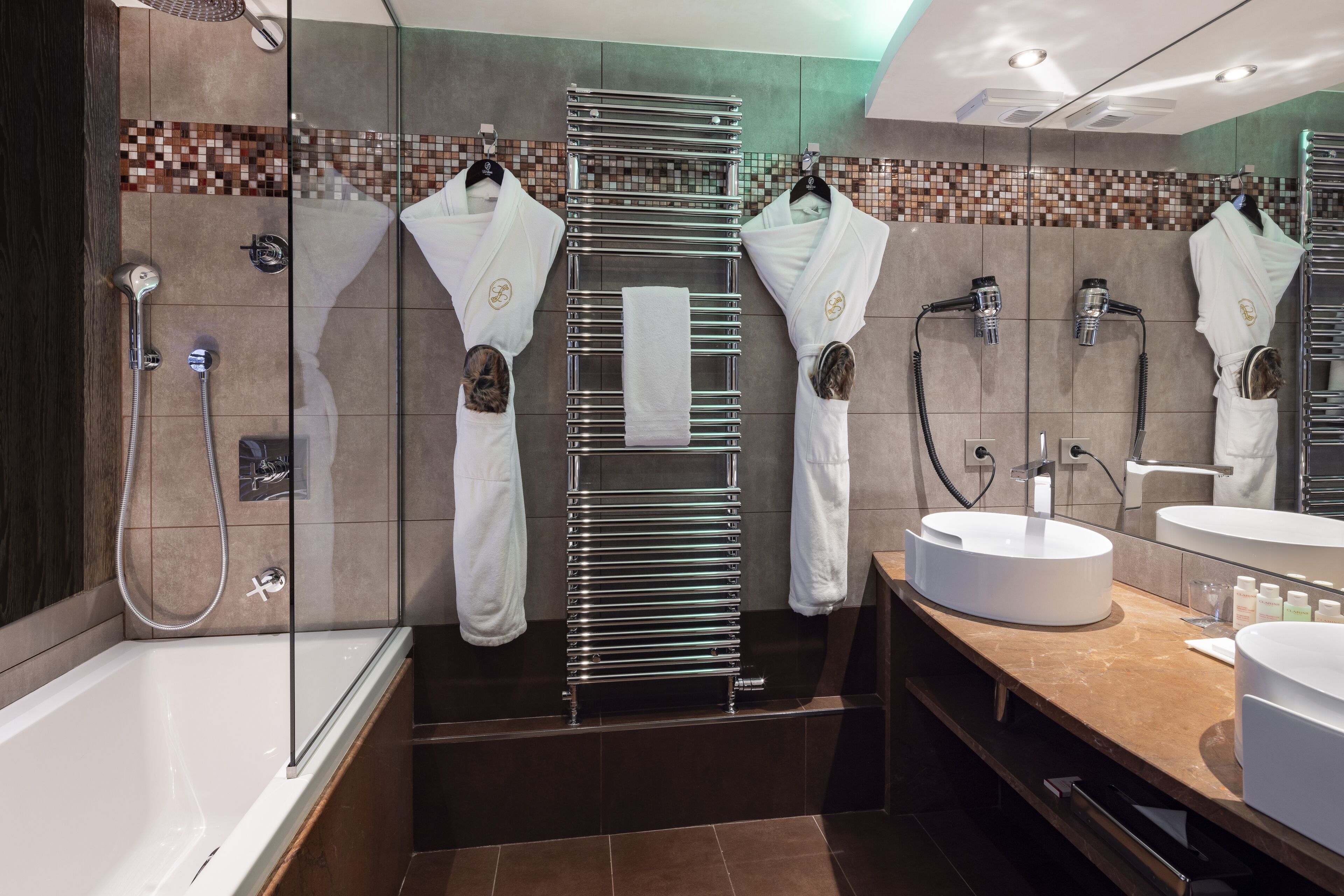 Une salle de bain moderne avec une douche à parois de verre, une grande baignoire, un meuble-lavabo doté d’un lavabo rond et un miroir.