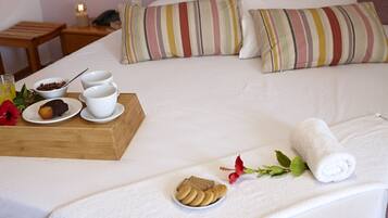 Cama bem arrumada com uma bandeja de itens de café da manhã, incluindo biscoitos e um muffin, e uma toalha enrolada sobre a cama.