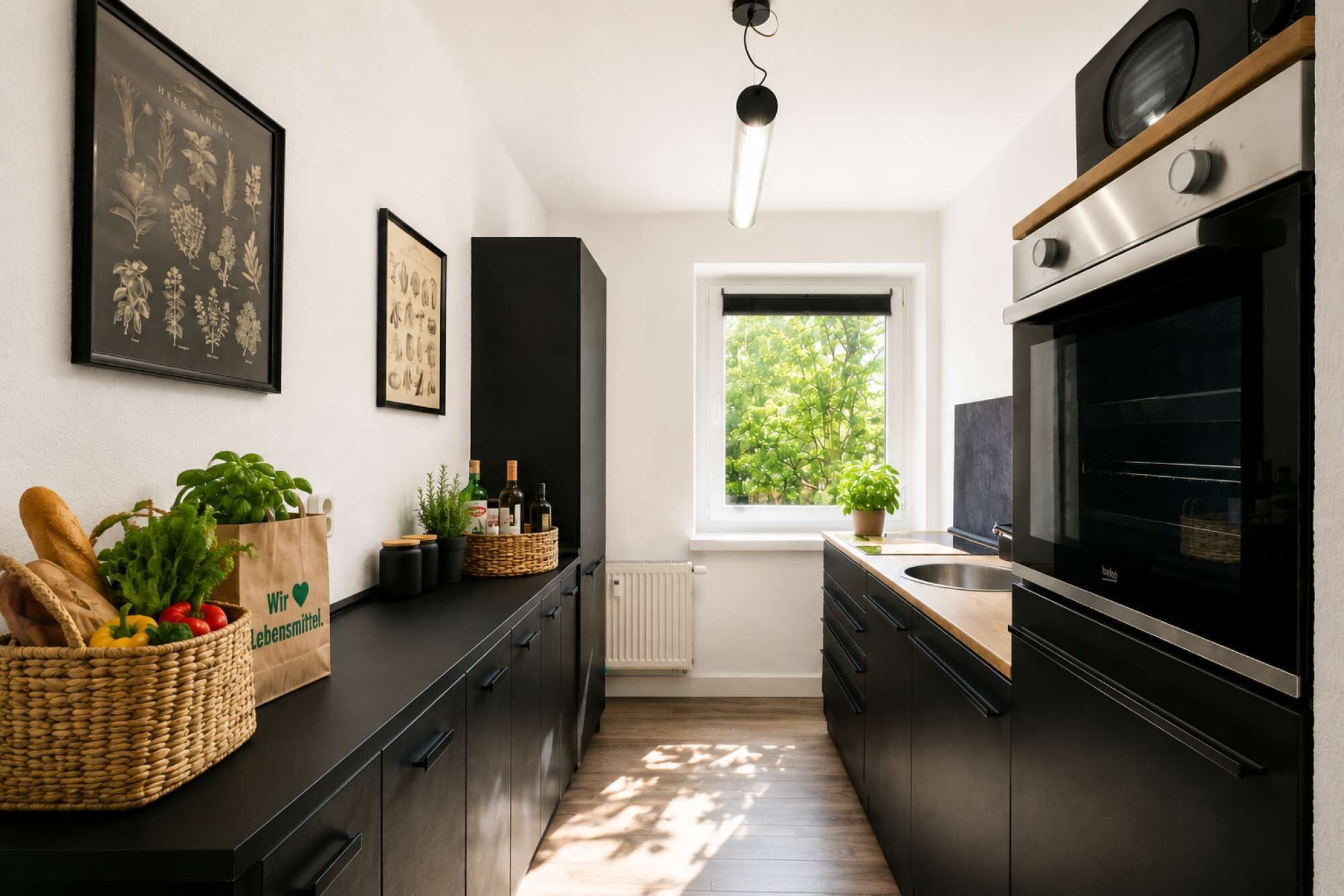Eine moderne Küche mit dunklen Schränken, einem großen Backofen und einem Fenster mit Blick auf Grünflächen.