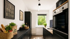 Een moderne keuken met donkere kastjes, een ruime oven en een raam met uitzicht op groen.