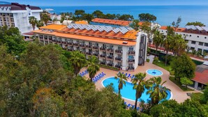 A hotel with multiple floors, a swimming pool, and a view of the sea. - Rios Beach Hotel (Kemer)