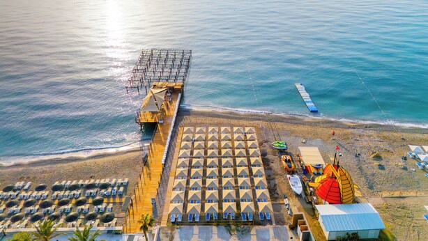 An aerial view of a beachside resort with a pier, sun loungers, and beach umbrellas. - Rios Beach Hotel (Kemer)