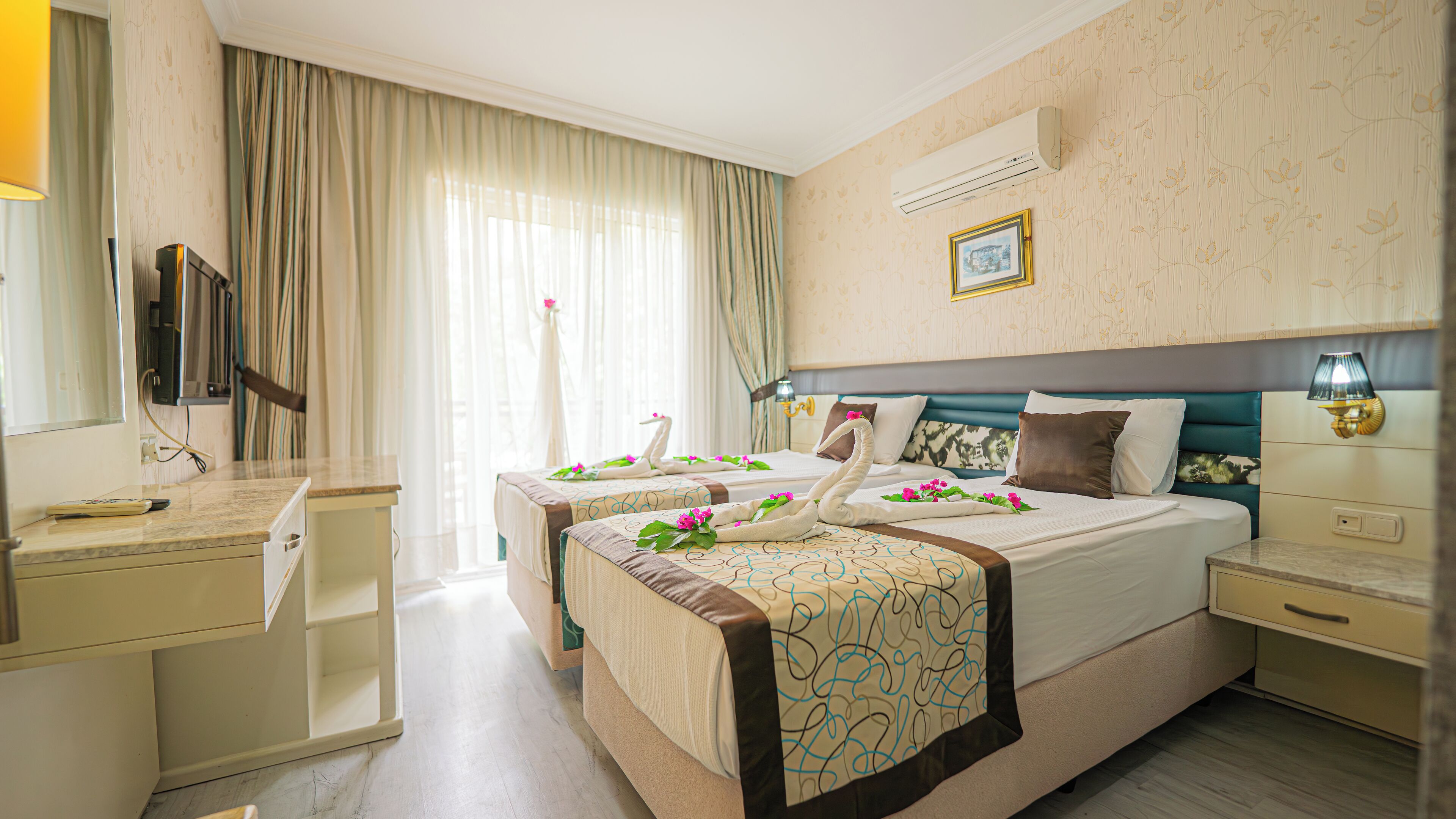 A hotel room with two beds, a TV, a desk, and a bathroom.