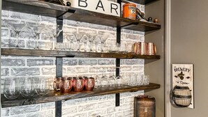 Eine Barbereitschaft mit Regalen voller Gläser und Tassen, ein Schild, das die Öffnungszeiten der Brauerei anzeigt, und eine rustikale Backsteinwand.