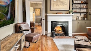 Ein gemütliches Wohnzimmer mit Kamin, Holzboden, Ledermöbeln und einem Bücherregal.