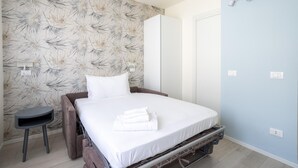 Een slaapkamer met een bed, een klein tafeltje en een kledingkast.