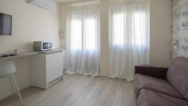 Een moderne, minimalistische woonkamer met een flatscreen televisie, een magnetron en een bank.