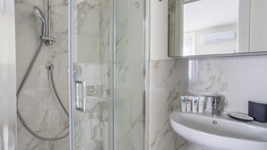 Een moderne badkamer met een douchecabine van glas, een witte wastafel en toiletartikelen.