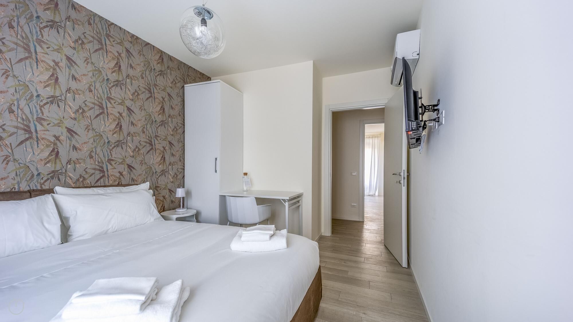 Ein Hotelzimmer mit einem großen Bett, einem Schreibtisch und einem Kleiderschrank.
