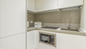 A compact kitchen with a built-in oven, a sink, and a small window. - Italianway - The B Village Superior - 46 (Milan)