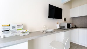 Een moderne keuken met een flatscreen-tv, een magnetron en een witte stoel.