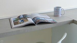 An open magazine on a table with a coffee mug beside it.