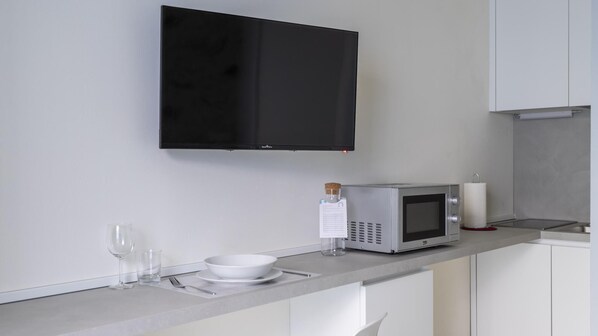 A modern kitchen with a flat-screen TV, a microwave, and a glass of water on the counter. - Italianway - The B Village Business - A23 (Milan)