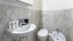 A bathroom with a marble backsplash, a white sink, a toilet, and a bidet. - Italianway - The B Village Business - A23 (Milan)