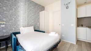 Ein Schlafzimmer mit Bett, Schreibtisch, Kleiderschrank und einer Küchenzeile.