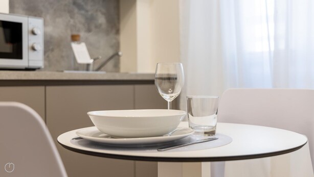 Une table à manger avec un bol blanc, un verre à vin et un verre à eau.