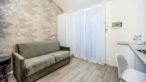 A room with a sofa, a desk, and a window with curtains. - Italianway - The B Village Standard - At03 (Milan)