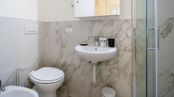 Un baño con inodoro, lavamanos y zona de ducha.