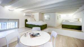Un dormitorio moderno y minimalista con una cama tapizada de verde, un sofá blanco y una mesa redonda con sillas.