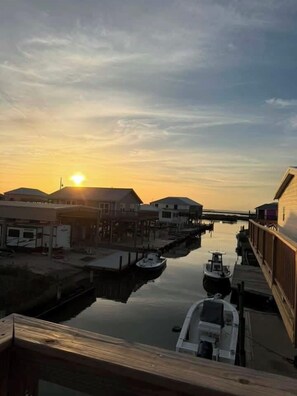 A marina with boats docked, a wooden walkway, and buildings in the background. - Afrayed Knot Waterfront- Coastal Realty Group (Grand Isle)