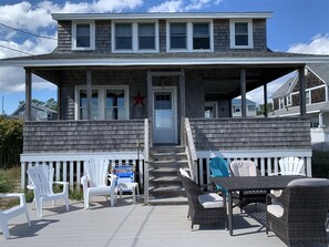 Relax on the covered porch with Adirondack chairs and a wicker table.