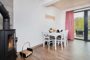 Una cocina moderna con estufa integrada, armarios blancos y una zona de comedor con mesa y sillas.