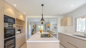 Una cocina moderna con electrodomésticos integrados, una isla central e iluminación colgante.