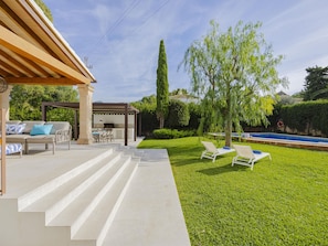 Une terrasse avec mobilier d’extérieur, un espace barbecue et une piscine.