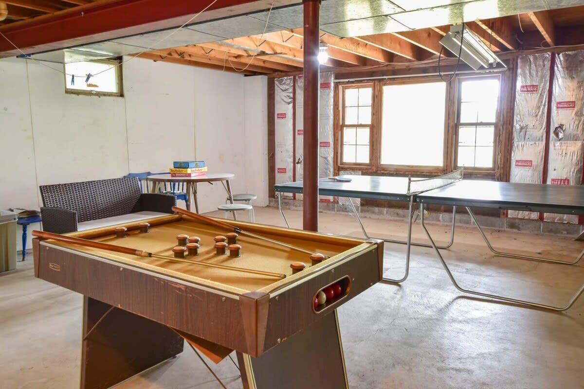 A room with a pool table, a foosball table, and a sofa.