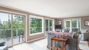 Un balcon spacieux avec de grandes fenêtres, un canapé gris et une petite table sur laquelle se trouve un plateau.
