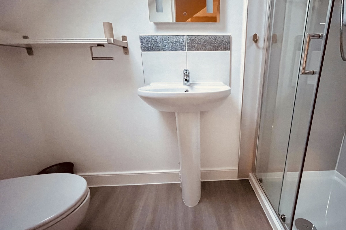 Une salle de bain avec un lavabo blanc, des toilettes et une douche à parois de verre.