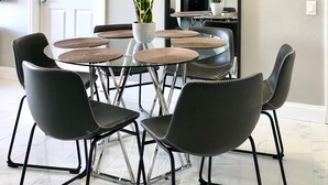 A dining area with a glass table, black chairs, and a modern chandelier. - 301 - Super Clean & Beautiful. Pools, Gym, Lake (Orlando)