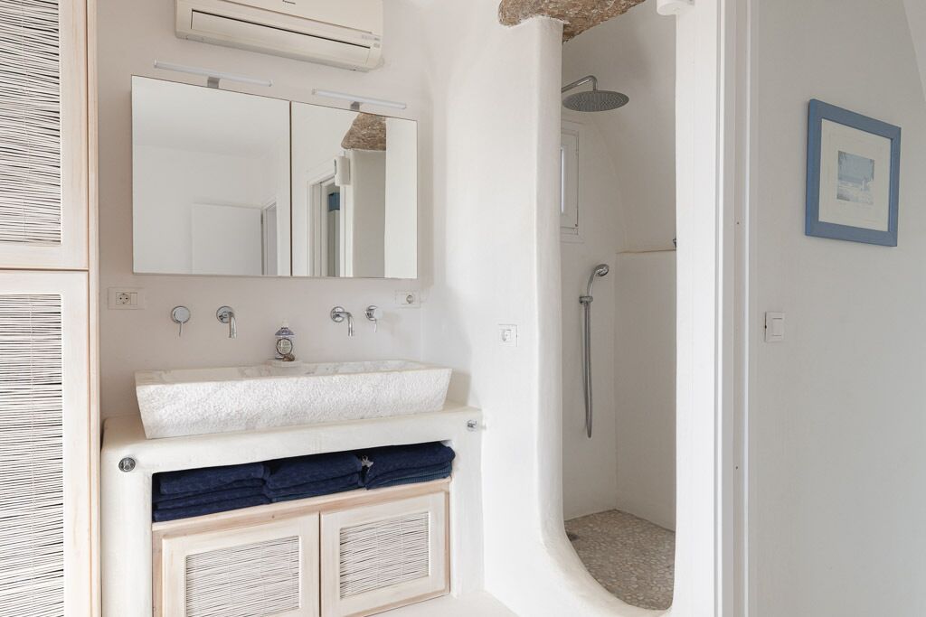 A bathroom with a white sink, mirror, and shower.