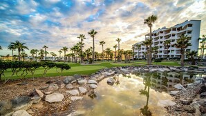 A resort with a pool, palm trees, and a golf course.