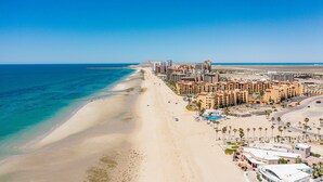 A coastal resort with beachfront hotels, a sandy beach, and a clear blue sea. - Casa Blanca Golf Villas 2 Bedrooms Condo E 212 (Puerto Peñasco)
