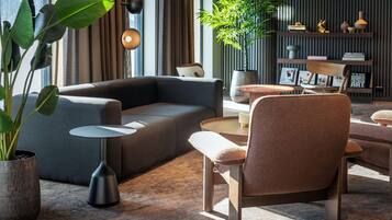 Una sala de estar moderna con un sofá, un sillón, una mesa de centro y plantas en macetas.